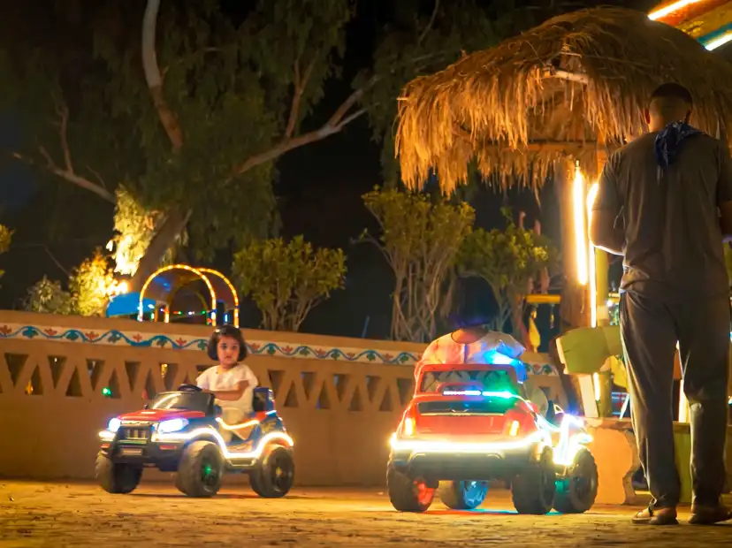 Happy children driving a mini electric jeep on the farm path