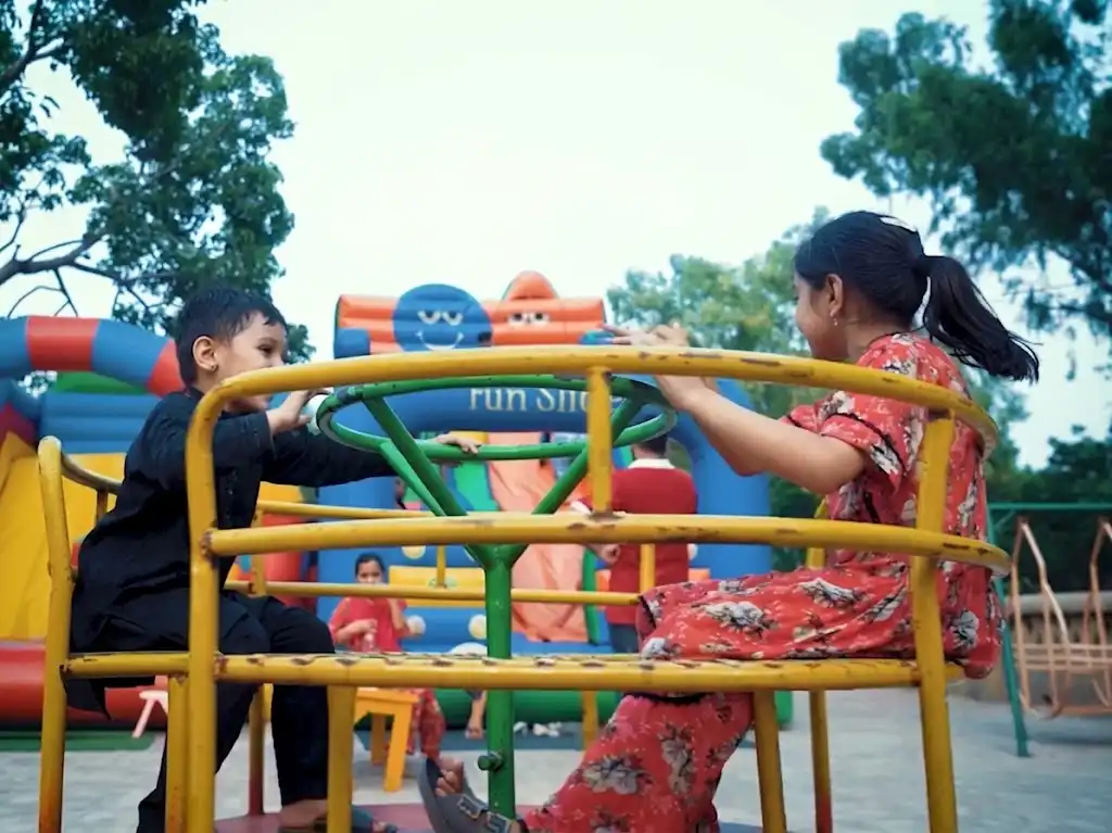 Happy children playing on a merry-go-round ride in kids playground