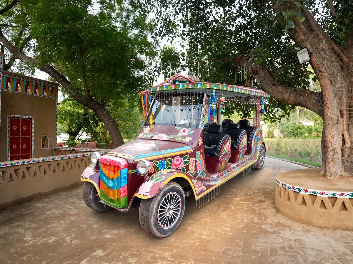 Detailed side view of the truck art golf cart parked beside a large banyan tree