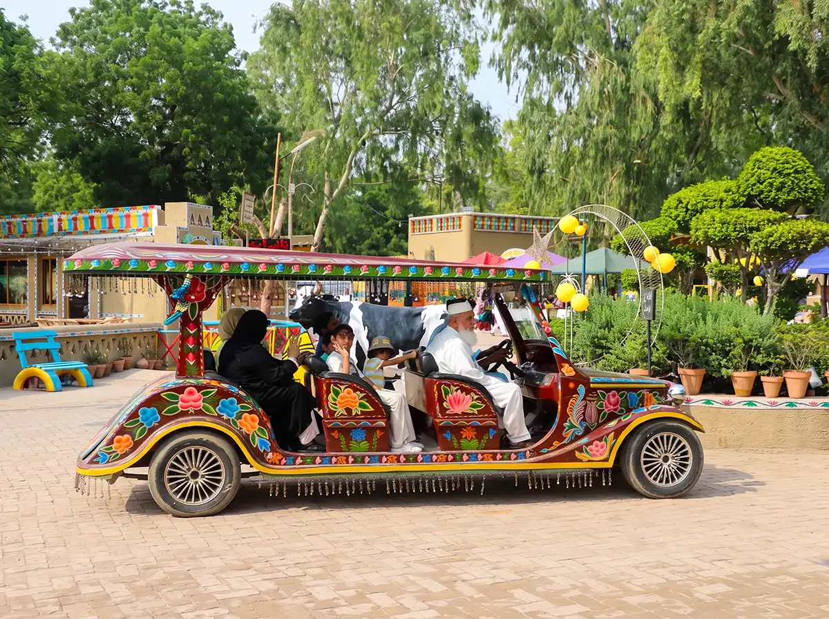 Family and passengers enjoying a scenic truck art golf cart tour under green trees