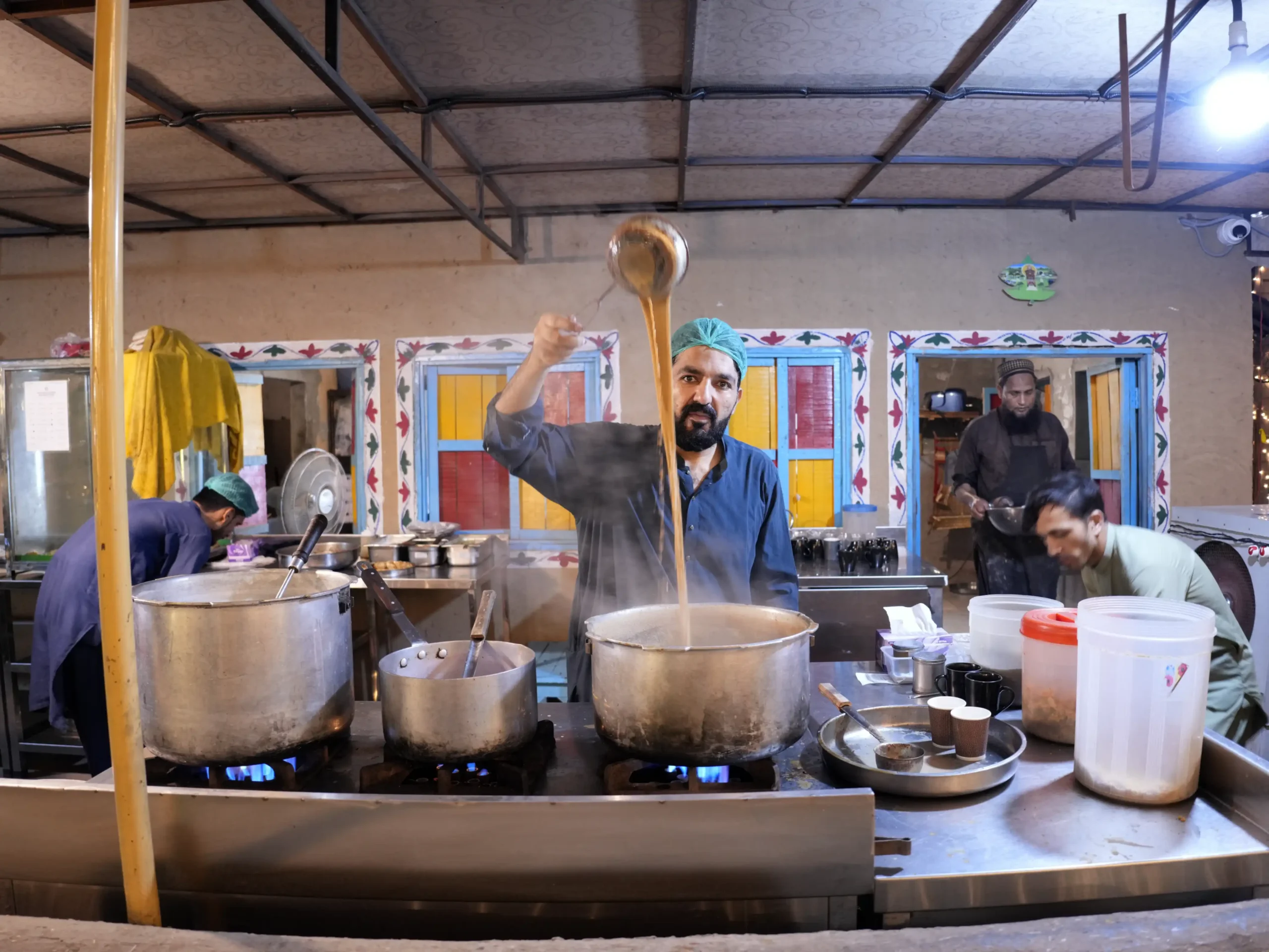 Foreign tourists being served traditional chai at an outdoor table at Chaye Dera in Lahore Organic Village