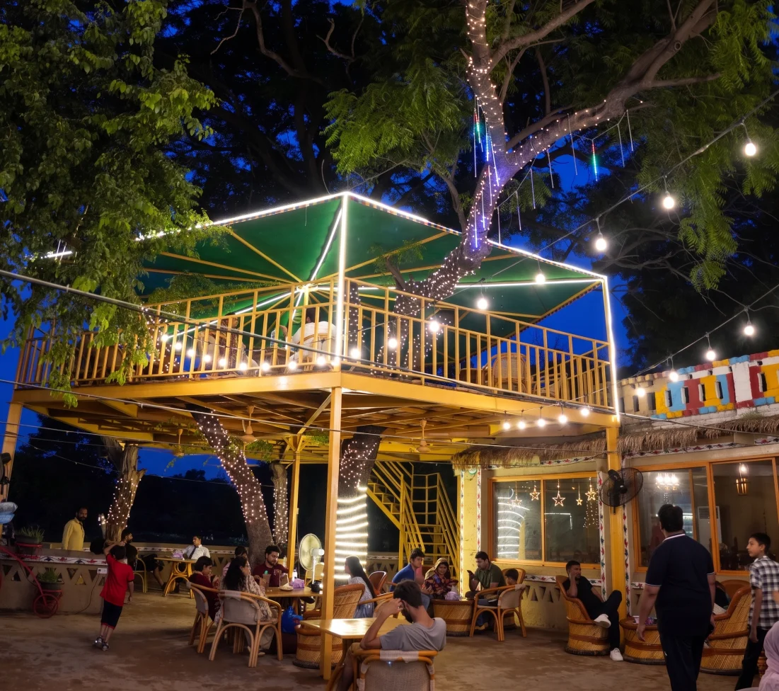 Tree house dining deck lit up at night at Desi Dhaba, Lahore Organic Village