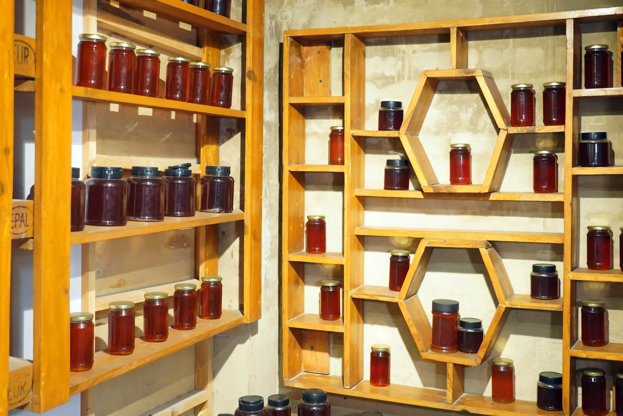 Wooden honeycomb display shelves stocked with pure organic honey jars inside Organic Aprico shop at Lahore Organic Village.