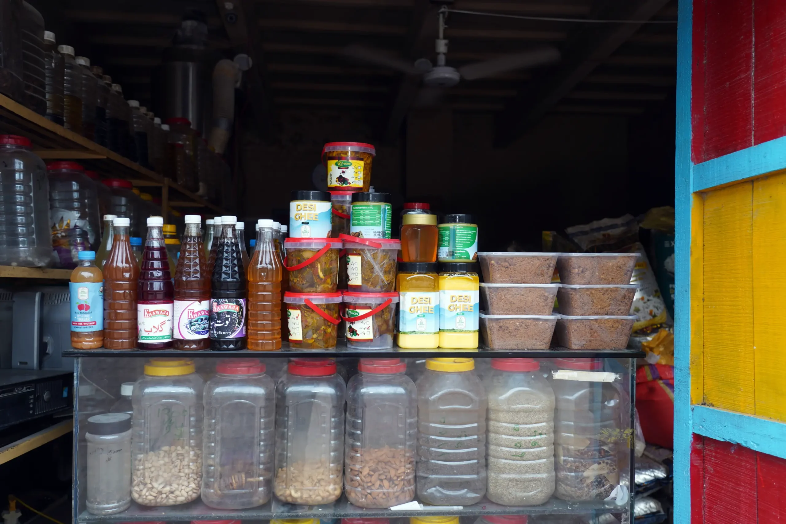 Shelves stocked with bottled drinks, organic desi ghee, pickles, and dried food jars.